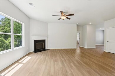Unfurnished living room featuring a ceiling fan, light wood-type flooring, a fireplace with flush hearth, baseboards, and recessed lighting