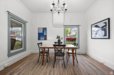 Dining room featuring ornamental molding, dark wood-style flooring, and a chandelier