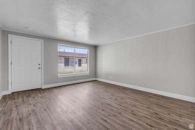 Entrance foyer with wood finished floors, ornamental molding, and a textured ceiling