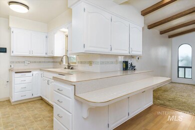 Kitchen with white cabinets, light countertops, beam ceiling, tasteful backsplash, and a kitchen breakfast bar
