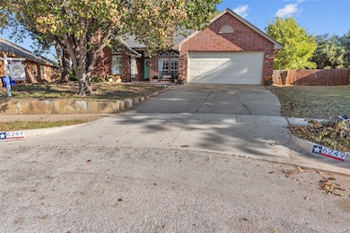 View of front facade featuring brick siding, driveway, and an attached garage
