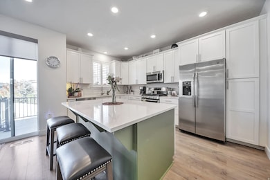 Kitchen with stainless steel appliances, white cabinetry, a center island, a kitchen bar, and recessed lighting