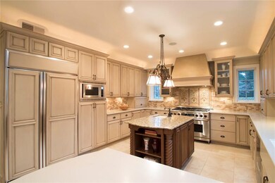 Kitchen Featuring Stainless Gas Stove, Island with Sink, and Breakfast Bar.