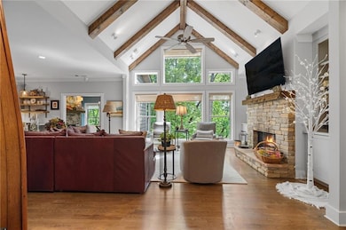 Living area featuring ceiling fan, healthy amount of natural light, beamed ceiling, high vaulted ceiling, and a fireplace