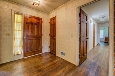 Foyer with wallpapered walls, dark wood-style floo