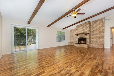 Unfurnished living room with a brick fireplace, light wood-style flooring, and ceiling fan