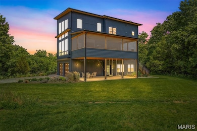Rear view of house with a patio, a sunroom, an attached garage, a lawn, and stairway