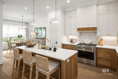 Kitchen with brown cabinetry, high end stainless steel range oven, dark wood finished floors, decorative light fixtures, and backsplash