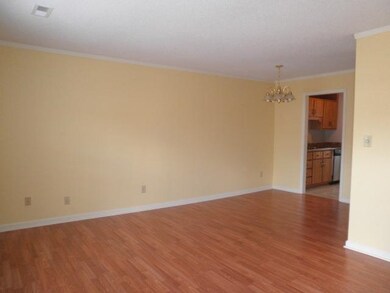The open living room has laminate flooring and a place for a breakfast table. It leads to the kitchen and the laundry room.
