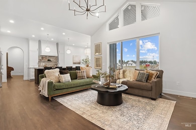 Living area featuring high vaulted ceiling, arched walkways, a chandelier, recessed lighting, and dark wood-type flooring