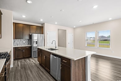 Kitchen featuring backsplash, stainless steel appliances, a center island with sink, dark brown cabinets, and recessed lighting