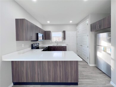 Kitchen featuring appliances with stainless steel finishes, a sink, light countertops, a peninsula, and recessed lighting