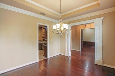 Unfurnished dining area with a chandelier, a raised ceiling, dark wood-style flooring, baseboards, and ornamental molding