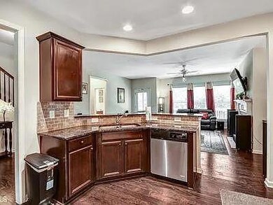 Kitchen with dark brown cabinetry, a peninsula, dark wood finished floors, dishwasher, and open floor plan