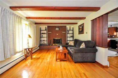 The beautiful living room with wood beams and beautiful hardwood floors! The fireplace is electric but could be wood burning as well.  Off to the right is the dining room/kitchen area.
