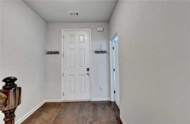 Foyer with dark wood-style floors and baseboards