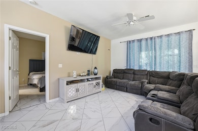Living room featuring light marble finish floors and a ceiling fan