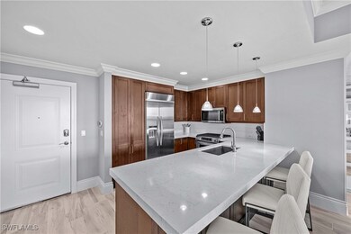 Kitchen with decorative light fixtures, appliances with stainless steel finishes, light stone counters, kitchen peninsula, and a kitchen breakfast bar