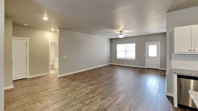 Unfurnished living room featuring dark wood-style floors and ceiling fan