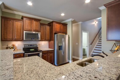 The kitchen features upgraded cabinetry, stainless appliances, pantry, granite counters, and open access to the dining and living rooms. 