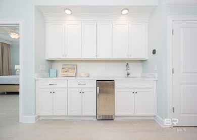 Kitchen with white cabinetry, stainless steel fridge, and light stone counters