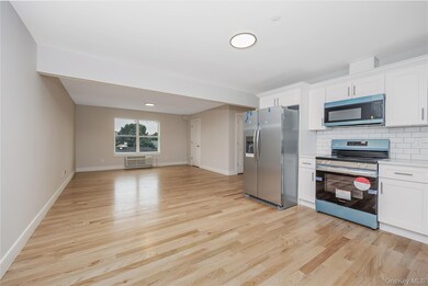 Kitchen featuring appliances with stainless steel finishes, white cabinetry, decorative backsplash, and light wood finished floors