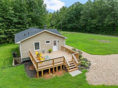 Rear view of house with a deck, a lawn, and centra
