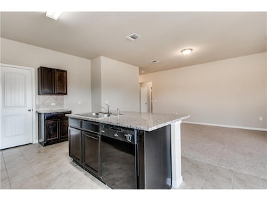 Kitchen featuring dark brown cabinets, dishwasher, a center island with sink, light tile patterned flooring, and backsplash