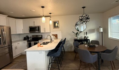 Kitchen featuring stainless steel appliances, a peninsula, tasteful backsplash, white cabinetry, and a textured ceiling