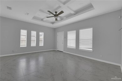 Tiled spare room with beamed ceiling, a tray ceiling, coffered ceiling, and ceiling fan