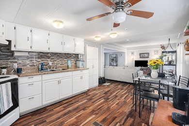 Kitchen featuring white cabinetry, electric range oven, dark wood-style floors, and light stone counters