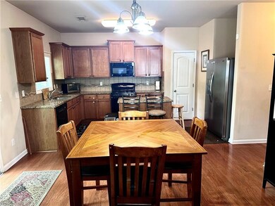 Kitchen featuring visible vents, wood finished floors, baseboards, black appliances, and a notable chandelier