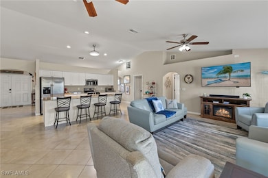 Tiled living room with ceiling fan and vaulted ceiling