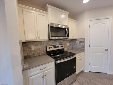 3 - Cream Cabinets, grey quartz counter, stone tile backsplash