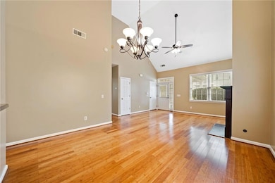 Unfurnished room with high vaulted ceiling, a chandelier, light wood-style floors, baseboards, and a ceiling fan