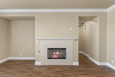 family room featuring a tiled fireplace, wood tiled floors, and ornamental molding