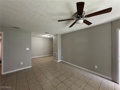 Empty room with a textured ceiling, a ceiling fan, and light tile patterned floors