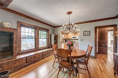 Dining room featuring light wood-type flooring, a notable chandelier, and ornamental molding