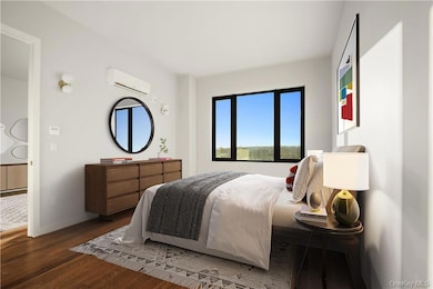Bedroom with dark wood-type flooring and a wall mounted air conditioner