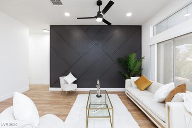 Living room with baseboards, a ceiling fan, wood f