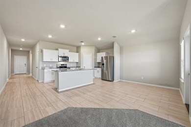 Kitchen with white cabinetry, stainless steel appliances, open floor plan, recessed lighting, and wood tiled floors