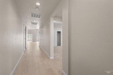 Corridor featuring a textured wall, a textured ceiling, and light wood-style floors