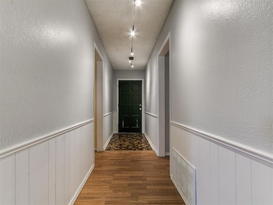 Hall with visible vents, wainscoting, a textured w