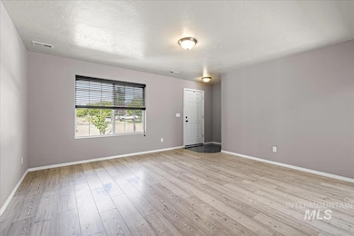 Empty room featuring light wood finished floors and a textured ceiling