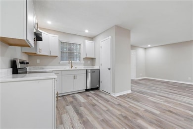 Kitchen with stainless steel dishwasher, fume extractor, electric range oven, white cabinets, and light wood-type flooring