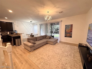 Living room featuring light wood-style floors, a chandelier, and recessed lighting
