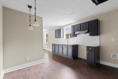Kitchen featuring under cabinet range hood, dark wood-style floors, backsplash, baseboards, and pendant lighting