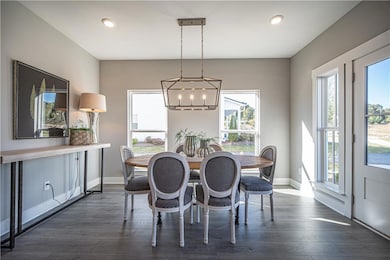 Dining area with a chandelier, dark wood-type flooring, baseboards, and recessed lighting