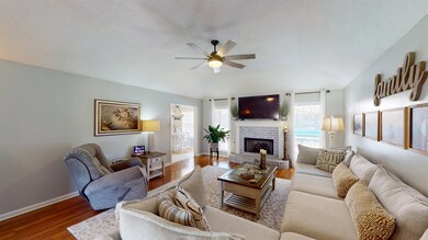 Living area featuring plenty of natural light, a ceiling fan, wood finished floors, a brick fireplace, and vaulted ceiling