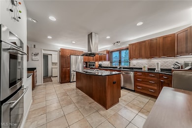 Kitchen with stainless steel appliances, light tile patterned floors, tasteful backsplash, recessed lighting, and a kitchen island
